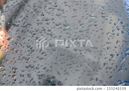 Raindrops delicately cling to a glass surface, creating a mesmerizing watery pattern Raindrops delicately cling to a glass surface, creating a mesmerizing watery pattern 133248339