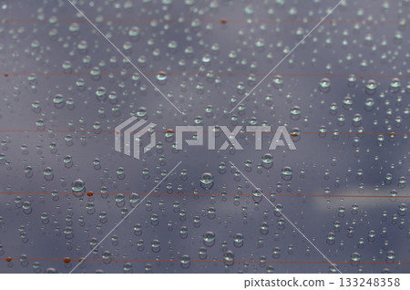 Raindrops create a mesmerizing pattern on a windowpane, reflecting the beauty of a cloudy afternoon Raindrops create a mesmerizing pattern on a windowpane, reflecting the beauty of a cloudy afternoon 133248358