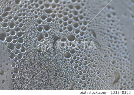 Dewdrops glisten on a dark surface under the soft light of dawn, creating a delicate atmospheric beauty Dewdrops glisten on a dark surface under the soft light of dawn, creating a delicate atmospheric beauty 133248393