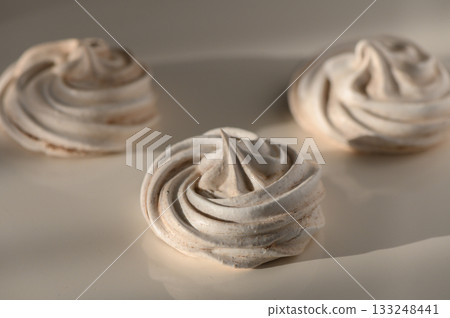 Sweet spirals of meringue resting on a soft surface waiting for a delightful taste experience Sweet spirals of meringue resting on a soft surface waiting for a delightful taste experience 133248441