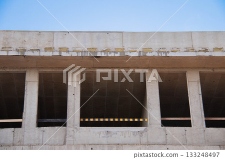Front view Concrete Wall Frame of Building under Construction. Formwork Prints with Thermal Pads, black-yellow Fence. Monolithic box window holes Construction Site. Architectural origin Structure. Front view Concrete Wall Frame of Building under Construction. Formwork Prints with Thermal Pads, black-yellow Fence. Monolithic box window holes Construction Site. Architectural origin Structure. 133248497