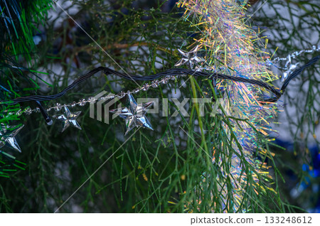 Bright silver stars illuminate a festive evergreen during the holiday season Bright silver stars illuminate a festive evergreen during the holiday season 133248612