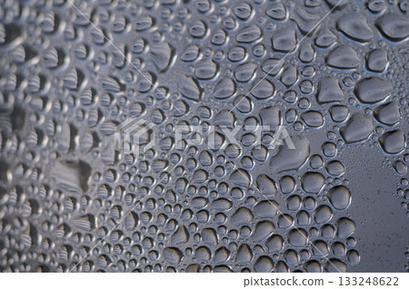 Raindrops gather on a window pane, creating a mesmerizing pattern of nature's artwork at dawn 133248622