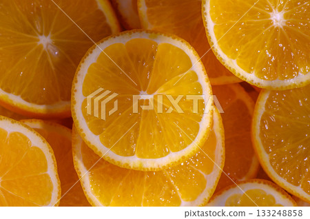 Freshly sliced oranges arranged beautifully under bright sunlight in a vibrant display of color and texture 133248858