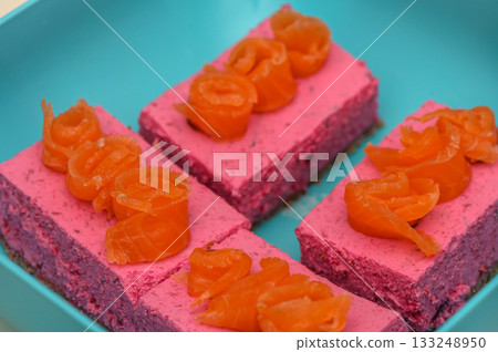 Delightfully vibrant dessert squares topped with candied orange curls on a bright blue plate 133248950