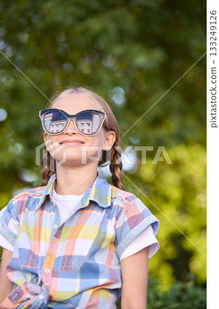 Caucasian young girl in sunglasses and plaid shirt enjoying sunny day outdoors Caucasian young girl in sunglasses and plaid shirt enjoying sunny day outdoors 133249126