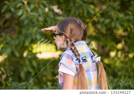 Young caucasian girl observing nature with hand shielding eyes in colorful Young caucasian girl observing nature with hand shielding eyes in colorful 133249127