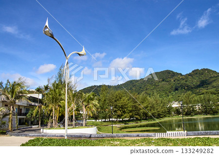 Lamp post against mountainous backdrop with blue sky and lush greenery 133249282