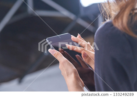 Female with long nails using smartphone indoors in close-up view 133249289