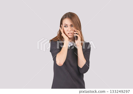Concerned young caucasian female speaking on smartphone against light Concerned young caucasian female speaking on smartphone against light 133249297
