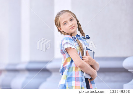 Caucasian young girl with braids holding books in plaid dress outdoors Caucasian young girl with braids holding books in plaid dress outdoors 133249298