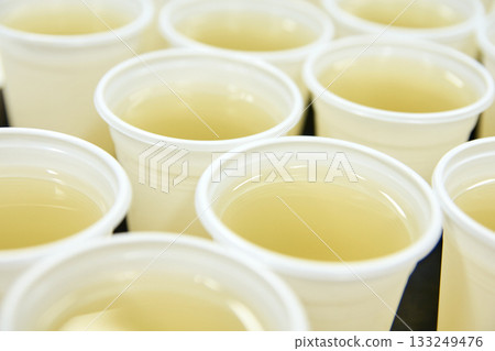 Rows of clear plastic cups filled with refreshing lemonade on a table 133249476