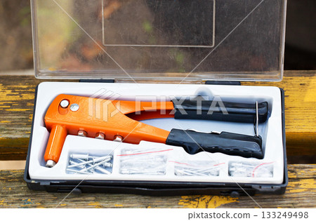 Tool kit with a rivet gun and assorted rivets for home repair projects 133249498