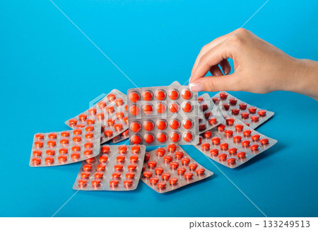 Blister pack with red pills in a female hand on a blue background. Concept of statin pills for lowering cholesterol in the blood. Copy space for text, bile acid sequestrants Blister pack with red pills in a female hand on a blue background. Concept of statin pills for lowering cholesterol in the blood. Copy space for text, bile acid sequestrants 133249513