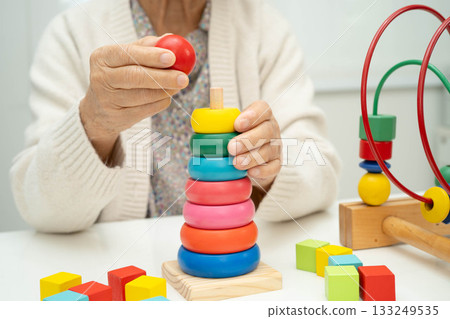 Asian elderly woman playing enhancing skill board game. 133249535