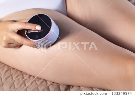 The girl does an anti-cellulite massage on her legs with a portable vacuum massager. Getting rid of flabby skin and cellulite, close-up, effective The girl does an anti-cellulite massage on her legs with a portable vacuum massager. Getting rid of flabby skin and cellulite, close-up, effective 133249574