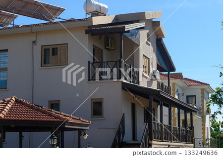 Bright sunny day highlighting a charming residential building surrounded by lush greenery and clear blue skies in a serene neighborhood 133249636