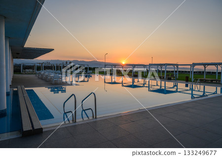 Serene sunset reflections over a tranquil swimming pool by the coast 133249677