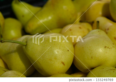 Fresh yellow pears stacked together in a vibrant farm market setting inviting taste and nourishment 133249769