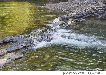 Clear stream flowing over rocks in forested area with rippling water Clear stream flowing over rocks in forested area with rippling water 133249833