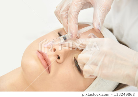 Female receiving cosmetic injection in nose by gloved hands in clinical setting Female receiving cosmetic injection in nose by gloved hands in clinical setting 133249868