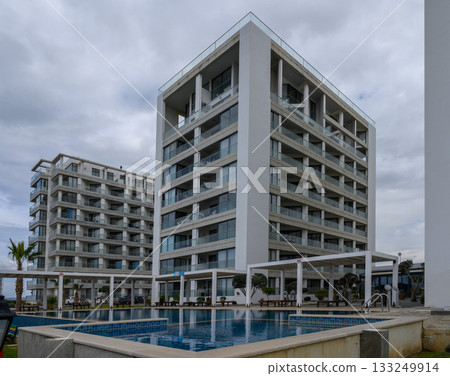 Modern beachfront apartments under cloudy skies overlooking a tranquil pool area Modern beachfront apartments under cloudy skies overlooking a tranquil pool area 133249914