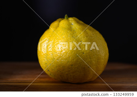 Vibrant yellow citrus fruit showcases unique texture and shape against a dark background Vibrant yellow citrus fruit showcases unique texture and shape against a dark background 133249959