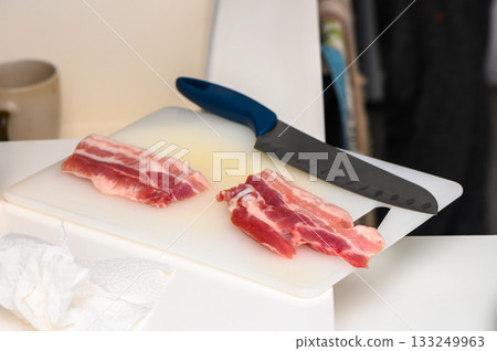 Slicing fresh cuts of meat in a modern kitchen during midday culinary preparation 133249963