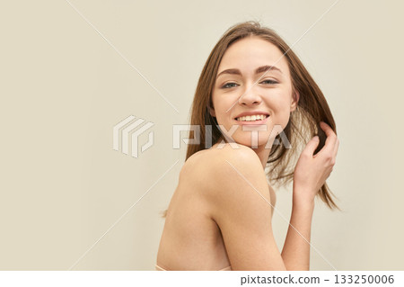 Smiling young caucasian female with brown hair posing against a neutral 133250006