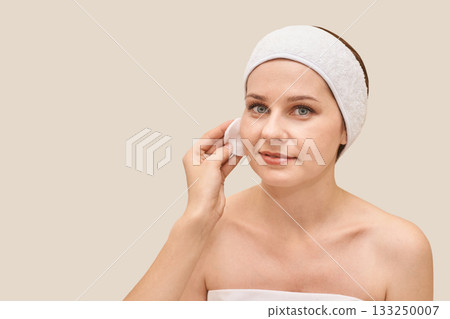 Female adult caucasian beauty skincare routine with cotton pad and headband 133250007