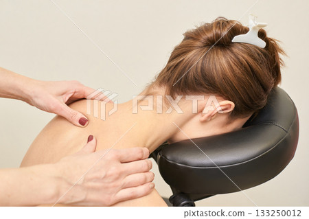 Female receiving relaxing massage therapy on neck and shoulders in spa setting 133250012