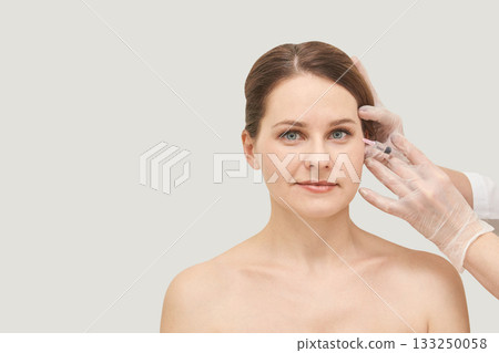Young caucasian female receiving cosmetic injection from gloved professional Young caucasian female receiving cosmetic injection from gloved professional 133250058