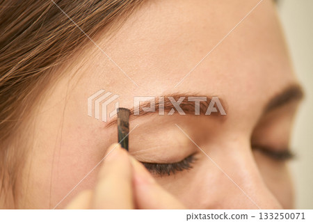 Close-up of young caucasian female applying eyebrow makeup for a natural look Close-up of young caucasian female applying eyebrow makeup for a natural look 133250071