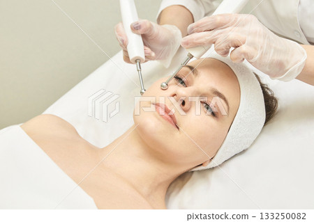Young caucasian female receiving facial beauty treatment with microcurrent 133250082