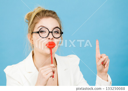 woman holds fake lips on stick pointing at copy space 133250088