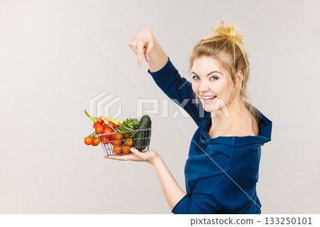 Woman holds shopping basket with vegetables Woman holds shopping basket with vegetables 133250101