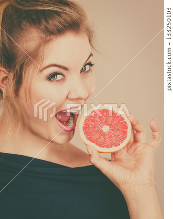 Happy smiling woman holding red grapefruit 133250103