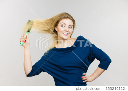Woman brushing her long hair with brush Woman brushing her long hair with brush 133250112