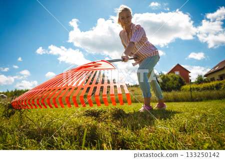Unusual angle of woman raking leaves 133250142