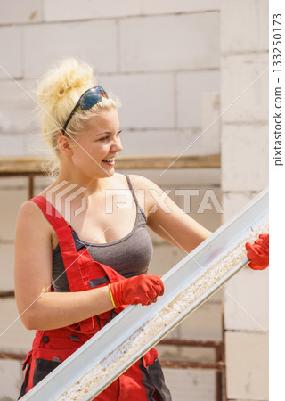 Woman carrying gutter on construction site 133250173