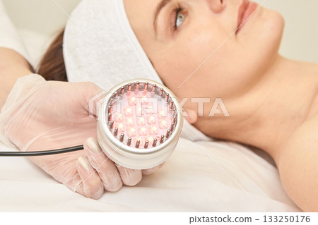 Young caucasian female undergoing facial led light therapy for skin Young caucasian female undergoing facial led light therapy for skin 133250176