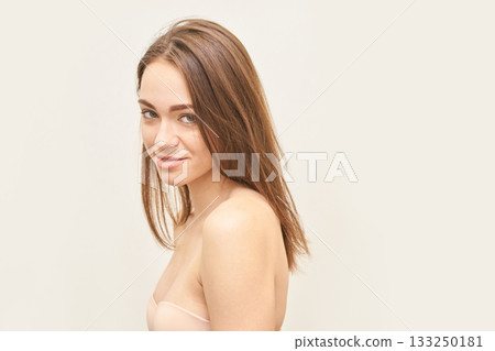 Young caucasian female with brown hair smiling in studio portrait with neutral 133250181