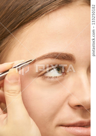 Young caucasian female receiving eyebrow tweezing beauty treatment close-up 133250182
