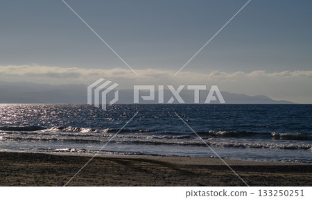 Gentle waves caress the shore as sunlight dances on the ocean's surface near Gentle waves caress the shore as sunlight dances on the ocean's surface near 133250251