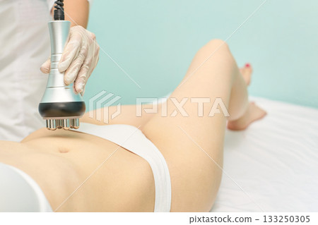 Female adult receiving body contouring treatment with rf machine in spa setting 133250305