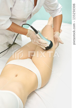 Caucasian female receiving professional body treatment with modern equipment Caucasian female receiving professional body treatment with modern equipment 133250306