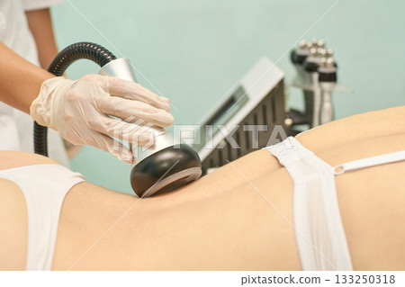 Cavitation treatment on female patient for body contouring performed by gloved Cavitation treatment on female patient for body contouring performed by gloved 133250318