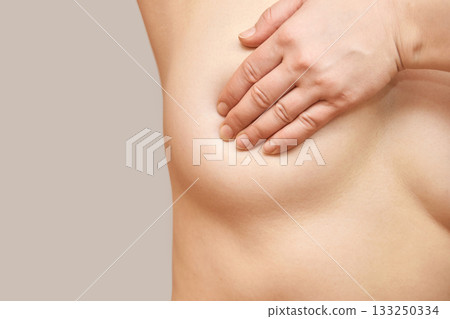 Female caucasian adult performing self-examination checking for breast health 133250334