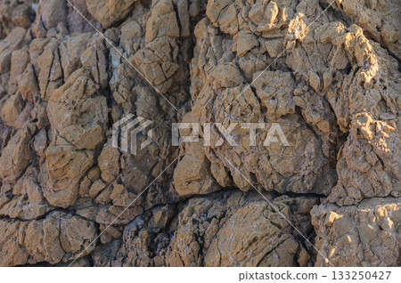Textured earth and cracked soil formations under bright sunlight in an arid landscape. 133250427