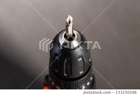 Close-up of a power drill showing the drill bit in focus against a dark background during a DIY project 133250586